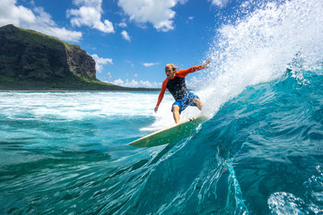 muscular surfer with long white hair riding on big waves on the Indian Ocean island of Mauritius