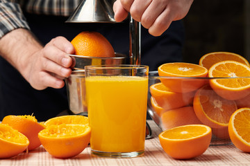 Squeezing an orange with a manual press, close view, making a glass of fresh. Fresh oranges on a...