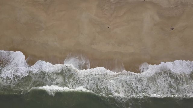 Flying over a sandy beach. Waves break on a sandy beach on the Atlantic coast, aerial View. Nazare, Portugal. (raw video).