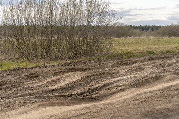 dirt damaged rural spring road in a field. concept of problem with the roads