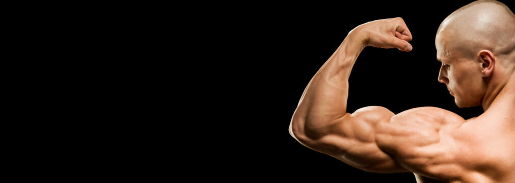 Close-up of a power fitness man's hand. Muscular bodybuilder flexing and showing his biceps - external side - on black background. Studio shot
