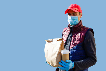 Delivery man in mask and gloves bring fresh food to customer's home. Stay home. Online shopping concept. blue background