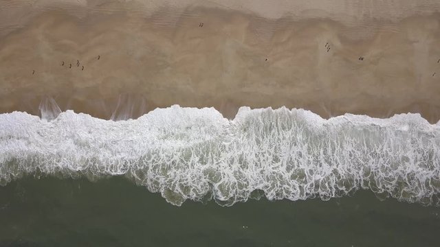 Flying over a sandy beach. Waves break on a sandy beach on the Atlantic coast, aerial View. Nazare, Portugal. (raw video).