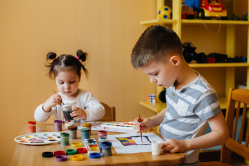A boy and a girl play together and paint. Recreation and entertainment. Stay at home