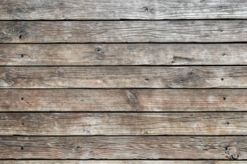 Close up of texture of wooden weathered boards with deep cracks driven with rusty nails into wall of rural house. Abstract background for design, blank template