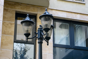 Three old style black metal street lamps on a pole