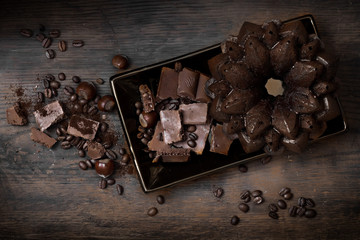 pieces of chocolate on a black plate on a dark wooden background. chocolate cupcake. spilled coffee beans