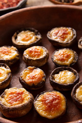 Roasted mushrooms with vegetables and parsley under melting cheese