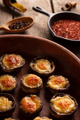 Roasted mushrooms with vegetables and parsley under melting cheese