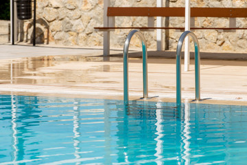 Fototapeta na wymiar Pool ladder reflected in blue water