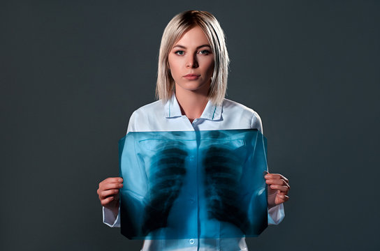 Female doctor holding chest x-ray isolated on dark gray background.