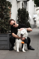 Portrait of a young man with a  Cute  beautiful  Samoyed dog in a park  with owner outdoors