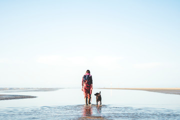 Frau geht mit Ihrem Hund am Strand der Nordsee spazieren