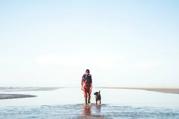 Zelfklevend Fotobehang Frau geht mit Ihrem Hund am Strand der Nordsee spazieren © Florian Kunde