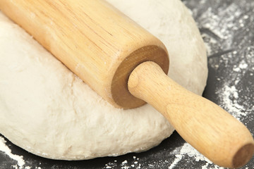 Dough and wood rolling pin on clean black background Close up