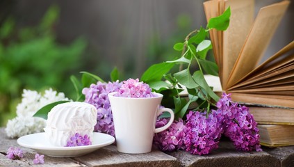 Cup of tea with lilac flowers on wooden background. Spring time. Vase with lilac. Copy space for text. The concept of holidays and good morning wishes.