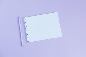 Notebook with blank page and pencil on a violet background.