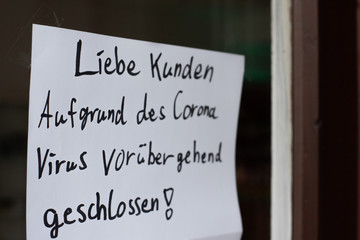 Bremen, Deutschland - 04/12/2020: Sign saying "Due to corona Virus temporarily closed." at a store front during pandemic for distance and infection rate reduction