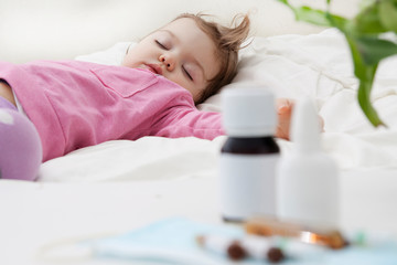 Fototapeta na wymiar Sleeping baby and medication in defocus. Baby treatment concept