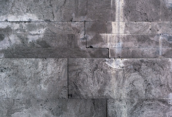 Old medieval grunge masonry. The texture of the facade is made of natural blocks in black and gray.