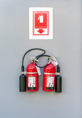 Two red fire extinguishers hanging on a white wall.