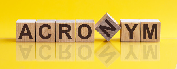 ACRONYM - word from wooden blocks with letters, sorry concept, yellow background.