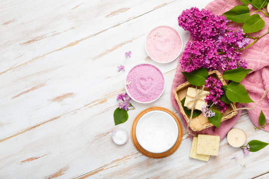 Natural cosmetics with lilac flowers. Serum, soap and cream. Face care products. Prepare to bath. Spa therapy concept photo. Organic cosmetic on wooden background. Cosmetics for relax and aromatherapy