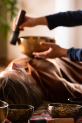 Woman making relaxing massage, meditation, sound therapy with tibetian singing bowls. Stress relief. Selective focus. Bottom view. 
