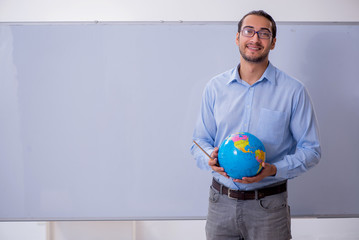 Young male geography teacher in front of whiteboard