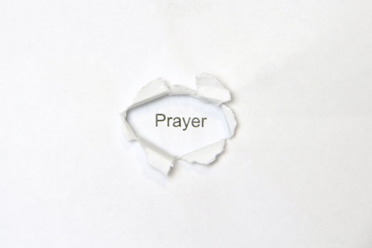 Word prayer on white isolated background, the inscription through the wound hole in the paper. Stock photo for web and print with empty space for text and design.