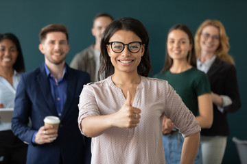 Portrait of african american businesswoman like gesture, showing thumbs up at camera. Different age diverse businesspeople standing behind of female company chief. Leader of multi-ethnic team concept