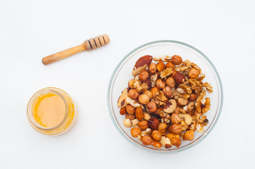Mixed nuts with honey . Brazil nuts, walnuts and hazelnuts on white wooden background. Healthy food concept. Vegetarian food. Raw food concept