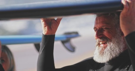 Close up senior man and woman carrying surfboards over head - Powered by Adobe