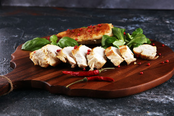 Partially sliced grilled chicken breast on cutting board on table