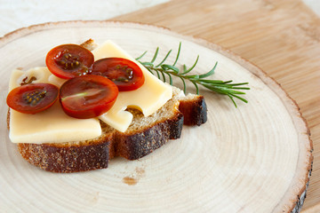 whole grain sandwich with cheese and tomatoes on a sawn wood board