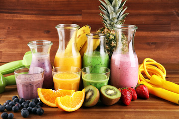 Obraz na płótnie Canvas Smoothie variation. Healthy lifestyle concept. sport fitness equipment-several bottles with fruit and berry juices smoothies or milkshakes with jumping rope