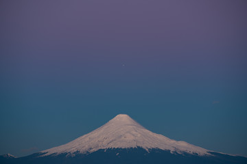 planet Jupiter aligned with the top of the Osorno volcano during the blue hour after sunset