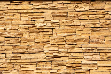 Texture of the yellow surface of a slate stone. Blocks of natural finishing stone for wall decoration. Rough stone background.