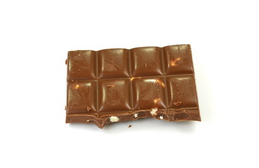 A broken piece of chocolate with hazelnuts isolated on white background. Milk chocolate tiles with nuts isolated on white.