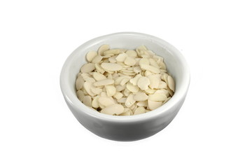 Pile of peeled flaked almonds isolated on white. Blanched almonds flakes on white.