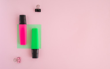 Flat lay with stationery pink and green marker, paper clips on pink background. Top view, copy space. Back to school, education, office concept.