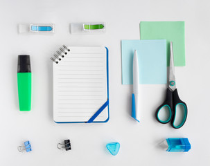 Flat lay with set of stationery: pen, pencil, copybook, notepad, scissors, marker, eraser, paper clips on white background. Top view, copy space. Back to school, education, office concept