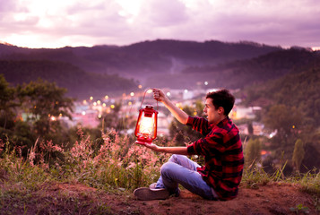 Person feeling free and enjoying life and watching the city lights with twilight sky.  kerosene lamp on.
