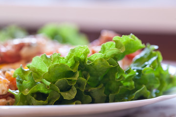 Soft focus. Dining table in a rural house in the kitchen. On the tablecloth is a plate with breakfast. Lettuce leaves, ham, eggs. Natural colors.