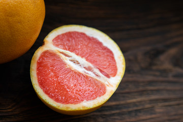Half a yellow red grapefruit on a dark wooden table.