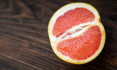 Half a yellow red grapefruit on a dark wooden table.