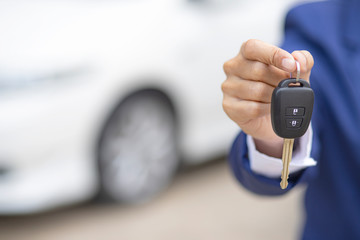 Close up of dealer giving key to new owner and shaking hands in auto show.