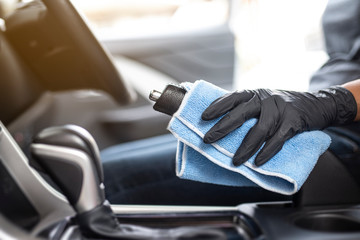 This image is a picture of wiping the car by a blue microfiber cloth with hand wearing gloves.