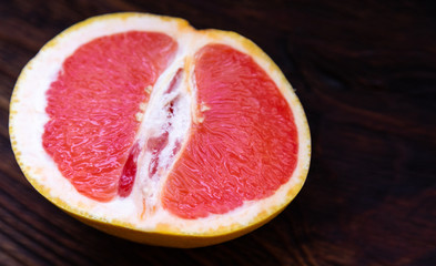 Half a yellow red grapefruit on a dark wooden table.