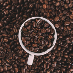 Americano coffee in a white cup and coffee beans in background. Coffee background out of focus...